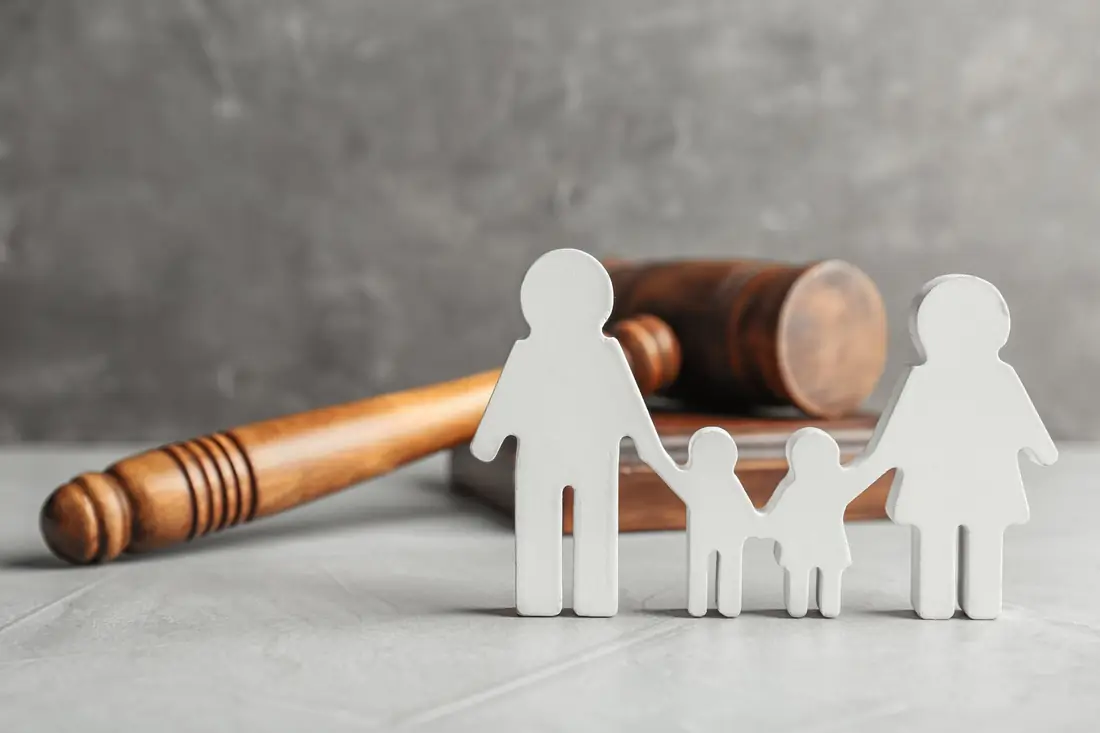 Wooden family figures in front of a gavel