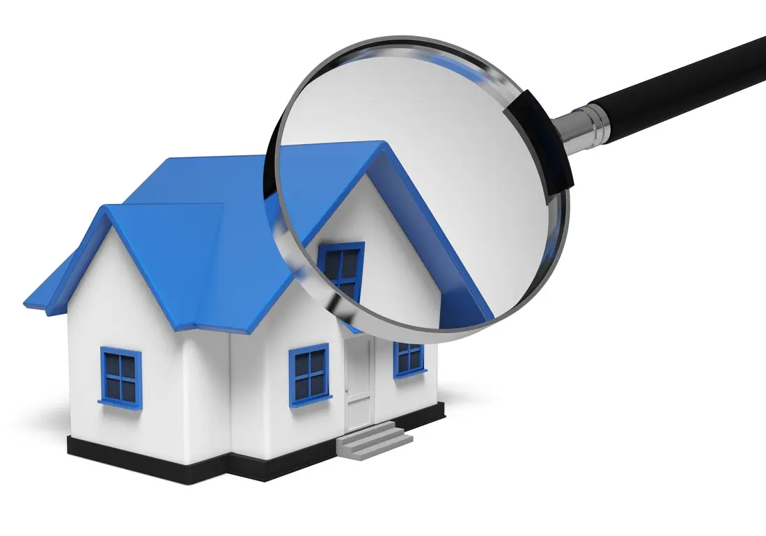 Magnifying glass held over a model house